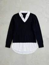 Buzo combinado con torso de tejido de punto fino en color negro y detalles de cuello y ruedo en gasa blanca que simulan una camisa debajo. Presenta escote en V y mangas largas.