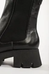 Bota tipo chelsea de caña media, color beige, con paneles laterales elásticos y suela track de plataforma dentada.