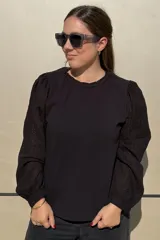 Remera de algodón con mangas largas abullonadas de tela bordada con detalles calados. Presenta cuello redondo con frunce y elástico, y puños elásticos.