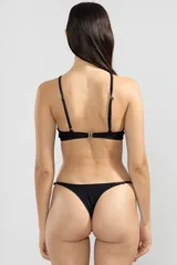 Conjunto de bikini negro con top halter con abertura en el centro y detalle de argolla dorada, y bombacha tipo colaless con tiras finas ajustables.