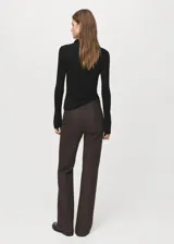 Jersey de punto color negro con cuello polo, cierre frontal parcial con botones y mangas largas.