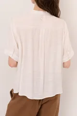 Camisa de manga corta color blanco con cuello mao y cierre frontal de botones. Presenta detalles bordados tono sobre tono en el canesú y diseño de corte recto.