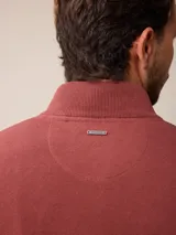 Sweater de punto color gris, con cuello alto y cierre frontal parcial con detalle de tela a cuadros en el interior. Presenta puños y ruedo acanalados y logo bordado en el pecho.