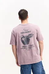 Remera oversize de algodón con efecto acid wash en color lila, de manga corta y cuello redondo. Presenta un gran estampado en la espalda con diseño de una manzana y textos alusivos.