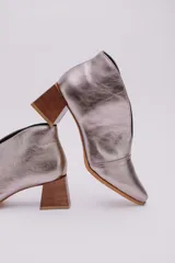 Botines de cuero color beige con diseño de tajo frontal, punta fina y taco cuadrado de madera.