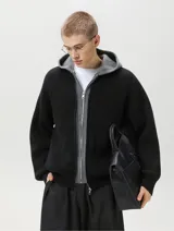 Campera de punto grueso acanalado en color negro con interior y capucha gris, diseño de doble capa y cierre frontal con cremallera.