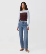 Pantalón de jean de corte recto y tiro bajo, color azul medio con efecto desgastado. Presenta bolsillos delanteros y traseros, y cierre frontal con botón y cremallera.