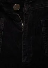 Pantalón tipo culotte de pana, color negro, de tiro alto con cierre de cremallera y botón. Presenta dos bolsillos de parche en la parte delantera y dos bolsillos de parche en la parte posterior.