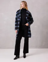 Tapado símil mohair, marca Dictionary, con estampado a cuadros en negro y azul. Tiene cuello con solapa, cierre frontal con botones y bolsillos delanteros. Incluye forro interno a tono.