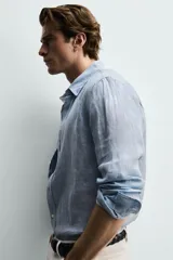 Camisa celeste de lino de corte regular fit, con cuello abotonado, manga larga y cierre frontal de botonadura.
