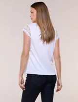 Remera blanca semi holgada de tejido suave, con escote redondo amplio, detalle de frunces en el centro del pecho y mangas cortas de crochet calado con bordes festoneados.