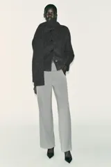 Pantalón recto color marrón oscuro, de tiro medio, con cintura elástica en la espalda, bolsillos delanteros de vivo y cierre frontal con cremallera, botón interior y gancho.