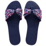 Sandalias tipo chinela Havaianas modelo You St Tropez, color azul marino. Presentan una base de goma texturizada y una tira superior de tela con diseño floral en tonos rosas y blancos, anudada en el centro.