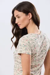Remera de manga corta con cuello redondo, confeccionada en algodón con estampa de diseño floral en tonos rosados y verdes sobre base beige.