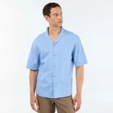 Camisa de manga corta de mezcla de lino en color celeste, con cuello cubano, cierre frontal con botones y un bolsillo aplicado en el pecho.