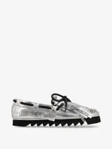 Zapato náutico plateado con flecos y cordones negros, y suela track negra.