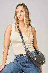 Cartera bandolera de cuero negro con diseño de media luna, decorada con tachas metálicas plateadas. Cuenta con correa regulable, cierre principal y bolsillo interior con forro.