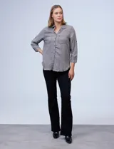 Camisa celeste de tencel con cuello con solapa, escote en V y abertura central con botones. Tiene bolsillos delanteros, mangas largas regulables con presilla y ruedo desflecado.