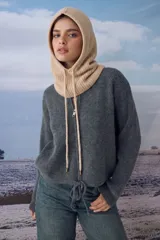 Gorro tipo balaclava tejido en color beige, con diseño ajustable mediante cordones frontales.