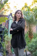 Camisa de punto calado en color beige con hilo de lurex. Presenta una silueta oversize, cuello camisero clásico, mangas 3/4 ligeramente abullonadas y cierre frontal con botones metálicos.