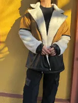 Campera marrón con mangas de corderito color crema y parte inferior de cuero sintético negro con textura de cocodrilo.