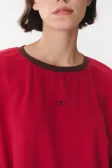 Remera de manga larga con corte oversized, color azul marino con cuello redondo en contraste color marrón. Presenta costuras decorativas a contratono hechas a mano en la zona de los hombros y logo bordado en el centro del pecho.