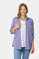 Camisa holgada de manga larga, color azul con rayas verticales blancas, cuello clásico y bolsillo en el pecho.