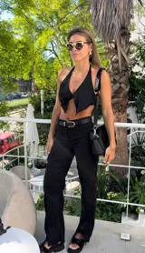 Pantalón negro de lino de corte ancho con aberturas en el ruedo y cintura con cinturón.