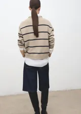 Jersey de punto de corte recto con diseño de rayas horizontales oscuras sobre fondo beige. Presenta cuello redondo, manga larga y tejido de punto medio.
