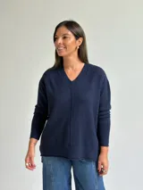 Sweater de punto en color azul marino, con escote en V, manga larga con puños acanalados y costura central vertical en el frente.