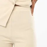 Pantalón de punto color beige, de corte flare con cintura alta y diseño ajustado en la parte superior que se ensancha hacia el ruedo.