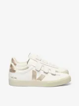 Championes Veja modelo Recife, de cuero blanco con cierre de tres tiras de velcro. Presenta detalles en color dorado metalizado en el logo lateral, el talón y la lengüeta. Suela de goma en tono crema.