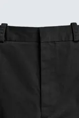 Pantalón chino de corte oversized confeccionado en tejido de algodón con estructura twill. Presenta bolsillos frontales, bolsillos traseros de vivo y cierre frontal con cremallera y gancho metálico oculto.