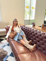 Cartera bandolera de cuero color camel, con forro interno de tela y flecos laterales.