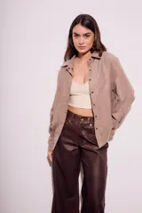 Camisa color marrón claro de gamuza vegana, corte oversize, con cuello clásico, cierre frontal con botones y mangas largas.