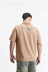 Remera polo color crema con logo bordado en el pecho, de corte amplio y mangas cortas.