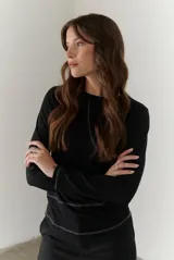 Remera blanca de manga larga con cuello redondo y costuras decorativas en contraste de color negro.