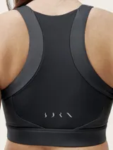 Top deportivo negro de sujeción media alta, confeccionado en tejido Shape_Tech con acabado satinado. Diseño con espalda deportiva.