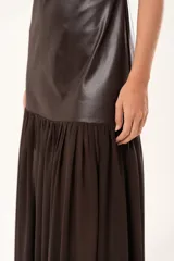 Vestido largo de escote cuadrado y tirantes finos. Presenta un diseño de dos texturas: cuerpo superior en tela engomada estructurada y falda inferior en gasa con sutil transparencia.