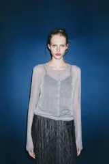 Chaqueta gris de punto fino semitransparente con hilo metalizado, cuello redondo, manga larga y cierre frontal con botones.