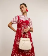 Cartera bucket pequeña de cuero sintético color negro, con doble asa (corta y larga), cierre con botón y detalle de hebilla.