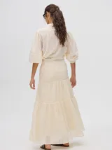 Falda larga confeccionada en broderie de algodón, con diseño de volados escalonados y detalles de galones con transparencias. Presenta una pretina elástica con cordones ajustables para un calce cómodo.