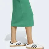 Vestido midi Adidas de corte ajustado, color verde, con mangas corta, cuello redondo blanco y las clásicas tres tiras blancas en los hombros.