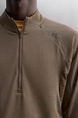 Sudadera negra de tejido técnico Polartec© con interior en estructura waffle. Tiene cuello alto con cremallera, mangas largas con puños ajustables con abertura para el pulgar y logo Polartec© bordado en el hombro.