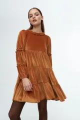 Vestido corto de terciopelo color cobre, con diseño de volados en capas, cuello redondo con detalle de volado y mangas largas con fruncidos.