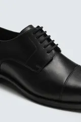 Zapato de vestir tipo Derby para hombre, color negro, fabricado en piel. Tiene horma redonda y suela con ligero tacón.