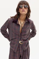 Camisa de lino con estampado escocés en tonos tierra, azul y rojo. Posee cuello con detalle de piel color púrpura y cierre frontal de botones.