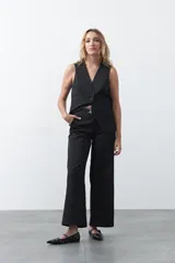 Pantalón wide leg de tiro medio, color negro, con diseño de sastrería y detalle de hebillas laterales con ojales metálicos en la cintura.