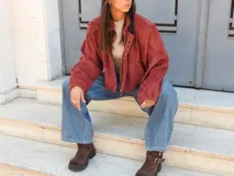 Campera tipo bomber color bordó, confeccionada en gamuza, con cierre frontal y una hilera de botones metálicos decorativos a lo largo de la solapa. Presenta mangas largas con puños holgados y un diseño de corte oversize.