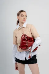 Cartera tipo bolso capitoneada de cuero color negro, con asa de cadena plateada y cuero entrelazado. Forrada por dentro y con bolsillo interno.